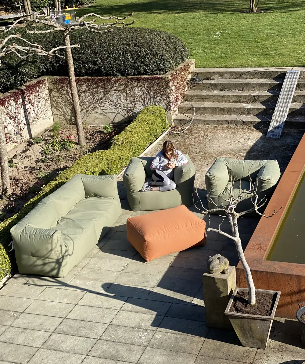 BRYCK loungeset met zachtgroene zitelementen en een oranje poef op een terras met trap
